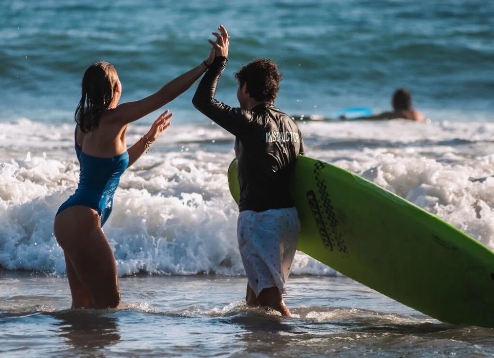 Two travelers carrying a surfboard into the ocean in Costa Rica