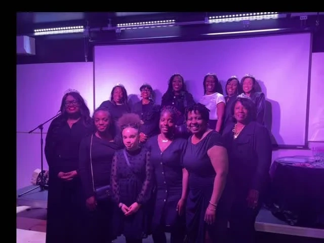 Group of women and girls together on a purple-lit stage