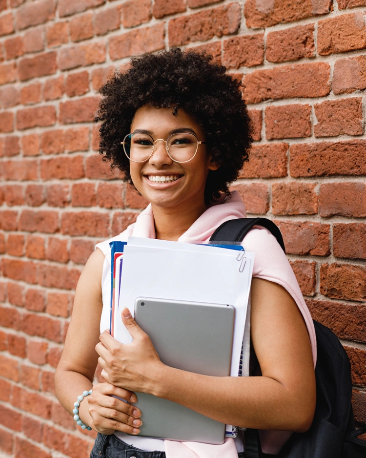 Young woman smiling while holding school materials
