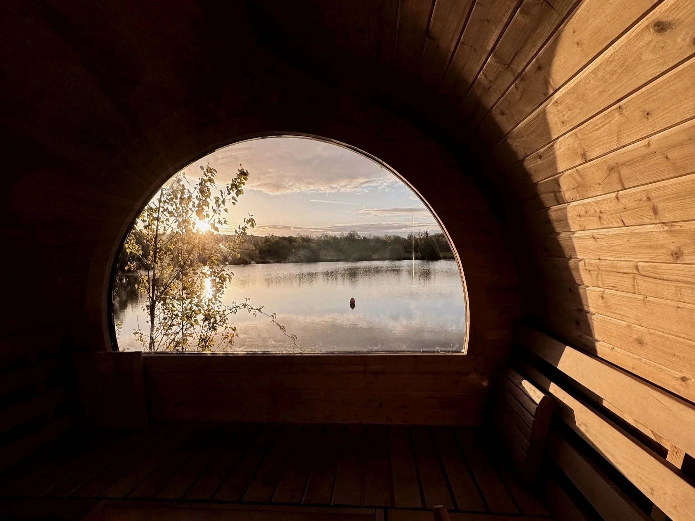Golden-hour lake view through a sauna arch