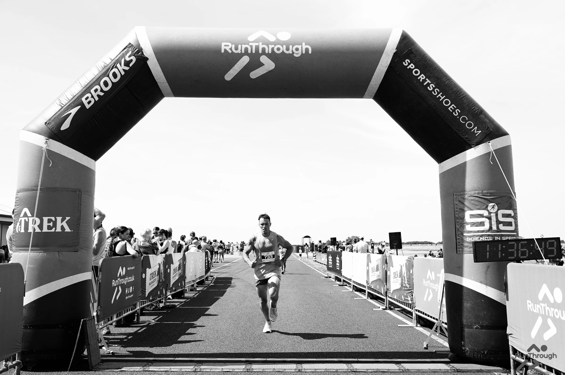 Ash Cox running through the finish line of a road race
