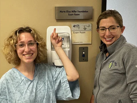 Marta Miller and a CHLA clinician beside the MEMF exam room sign