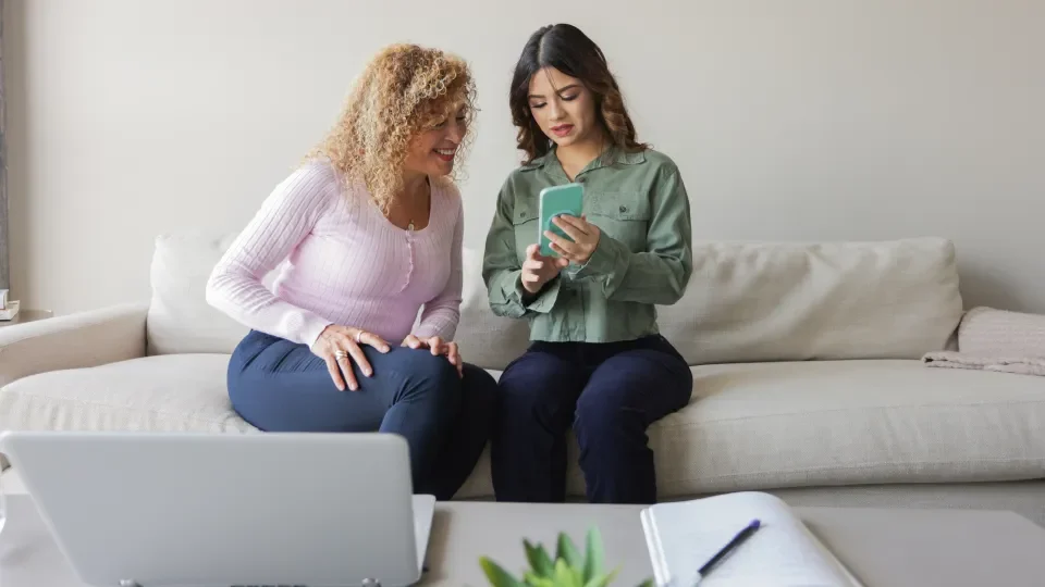 A teenager shares a smartphone with an adult while using the Momentum Spine app