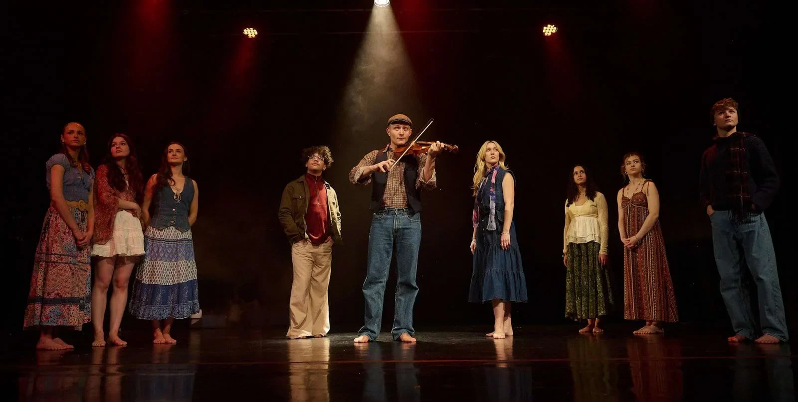 BUSK cast performing together on a warmly lit stage