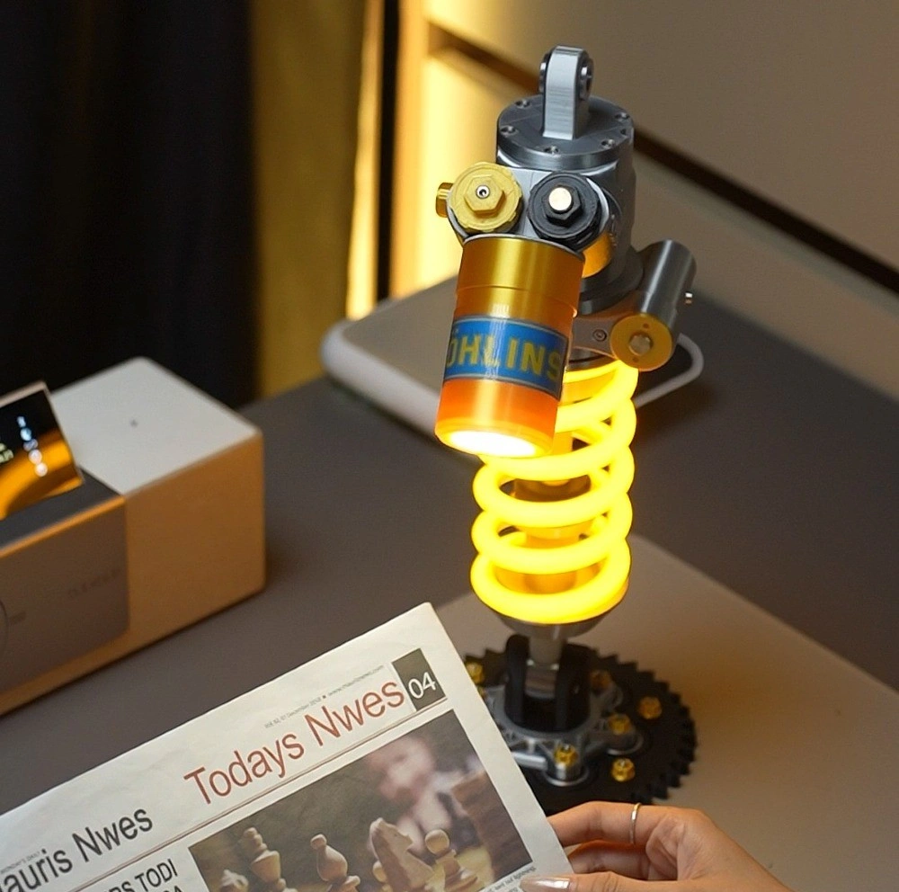 Öhlins-style shock absorber lamp glowing yellow on a desk