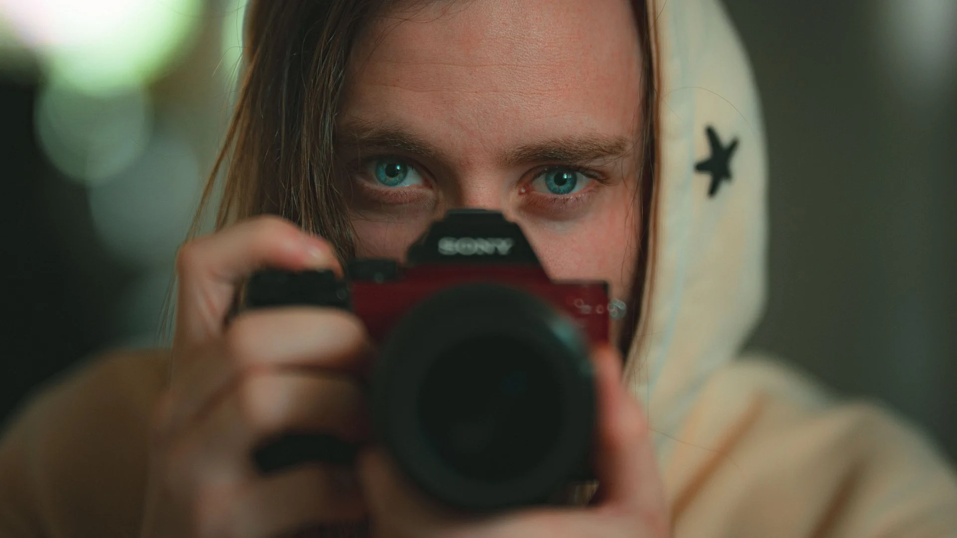 Marley holding a camera close to the lens in a cinematic portrait