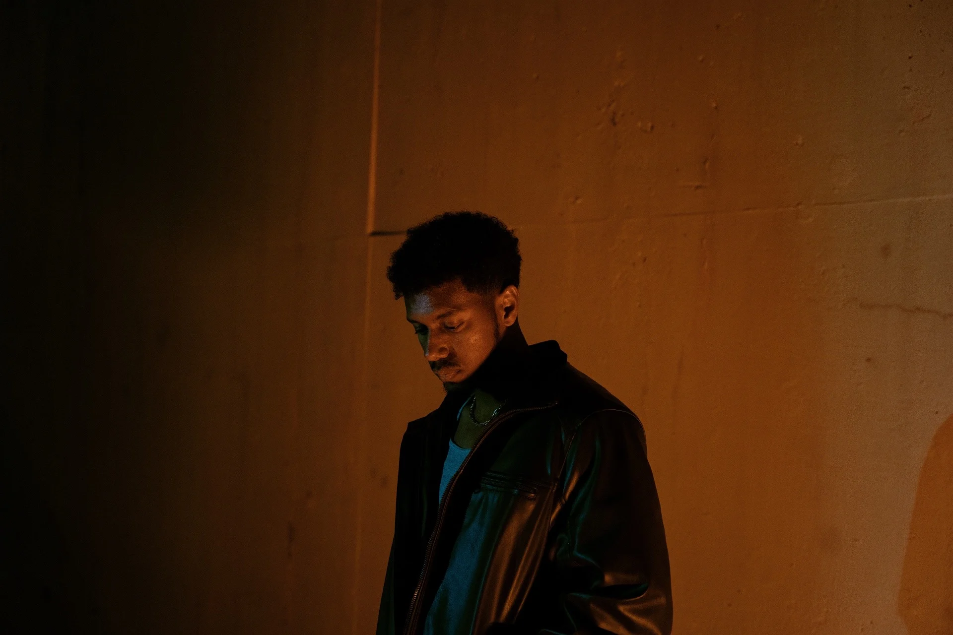 The Young One in a dark, green-lit portrait