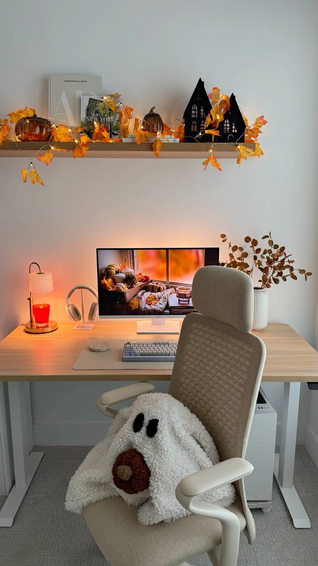 A desk with a fall leaf garland and a ghost pillow on the chair