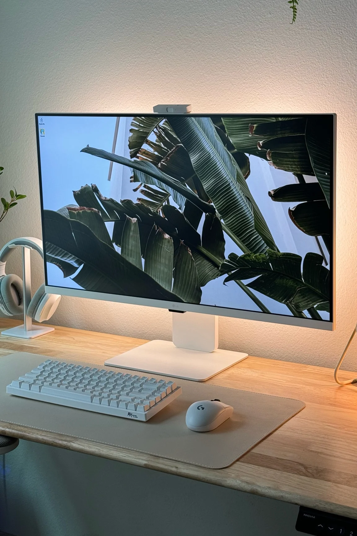 A white monitor and cream keyboard on a light wood desk