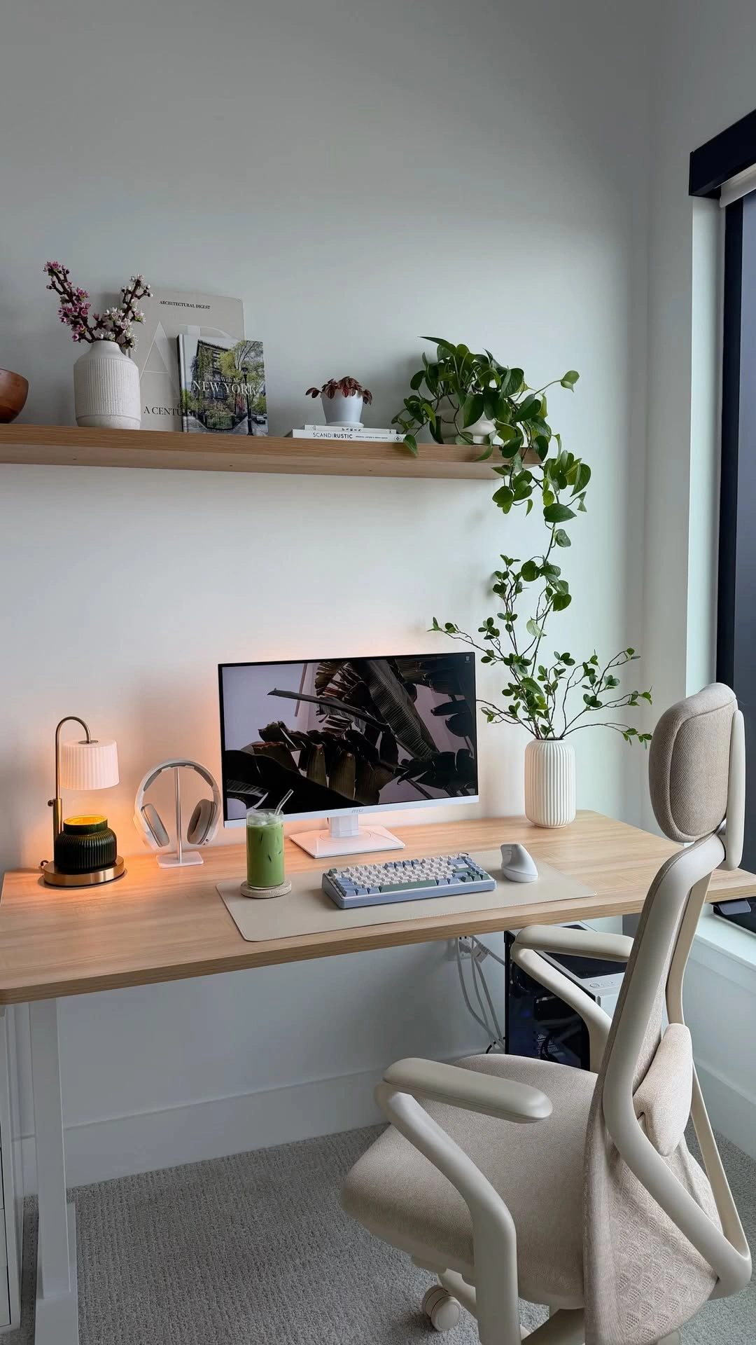 A cream desk setup with a trailing pothos, candle lamp and keyboard
