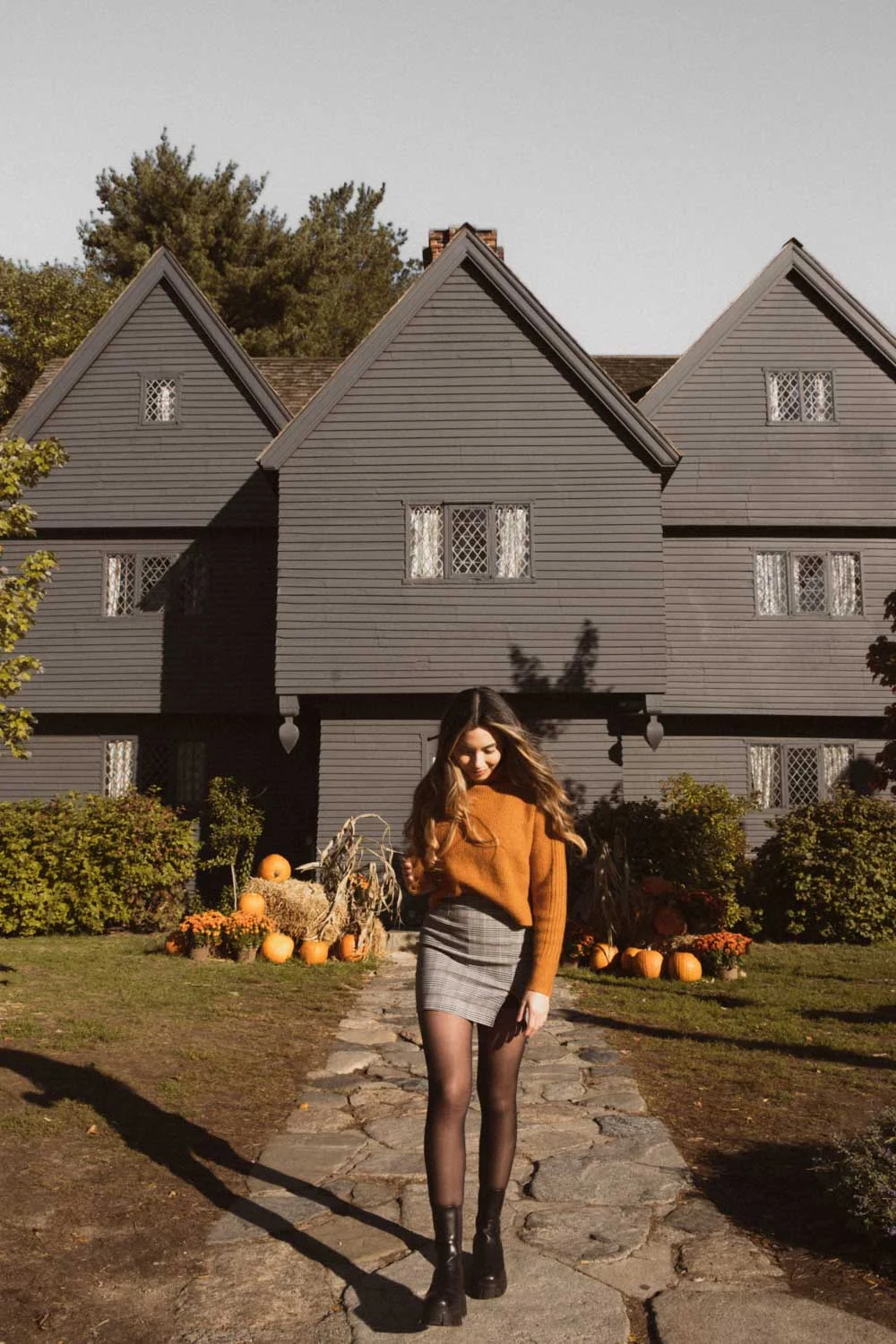 Arabella in an orange sweater outside the Witch House in Salem