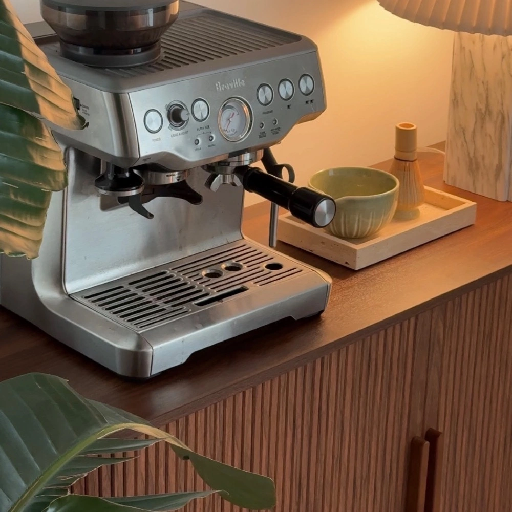 An espresso machine on a walnut sideboard
