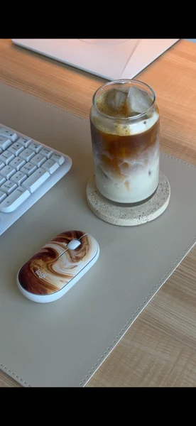 A latte-swirl Logitech mouse beside an iced latte on a desk mat