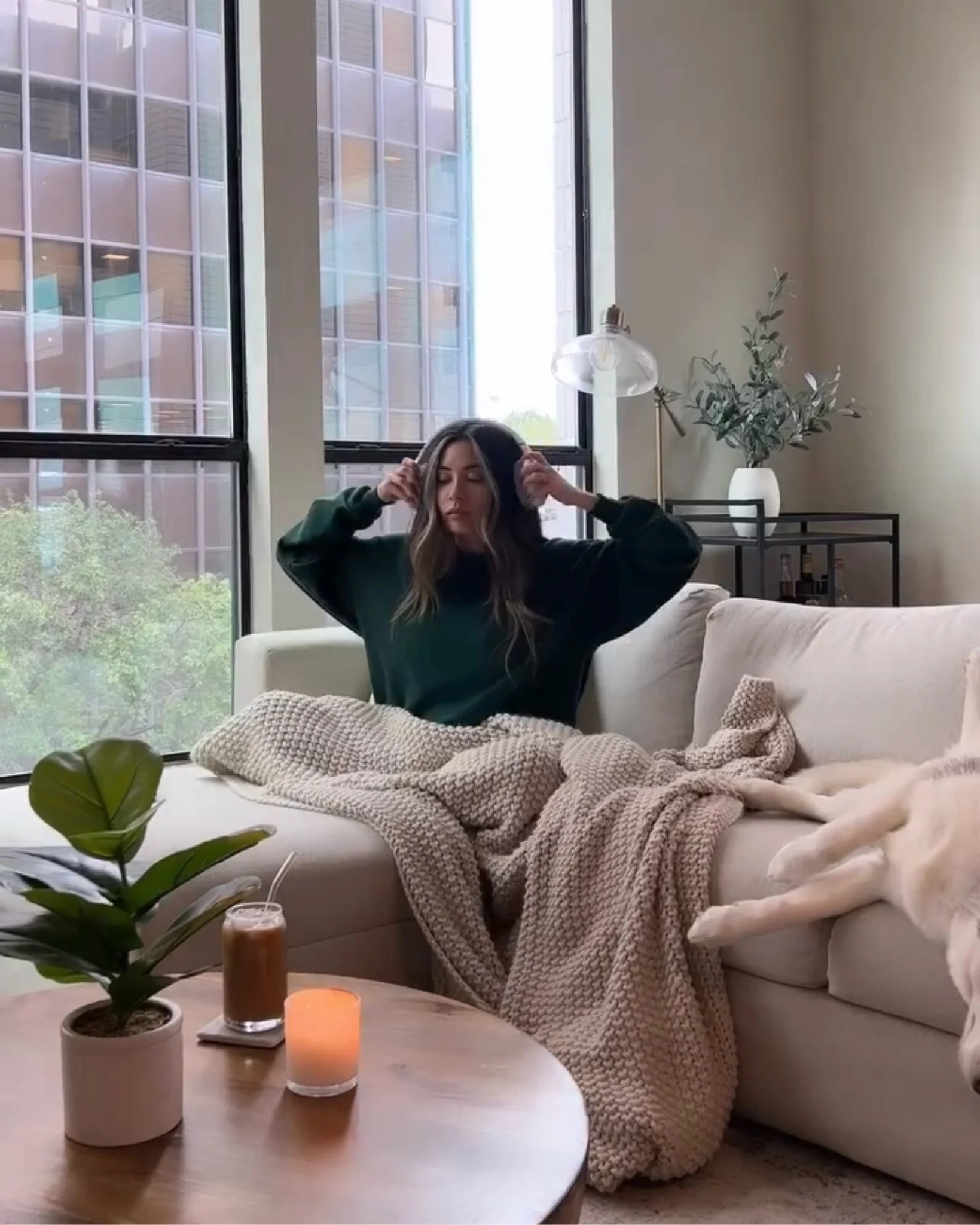 Arabella under a knit throw on a cream sofa by tall windows