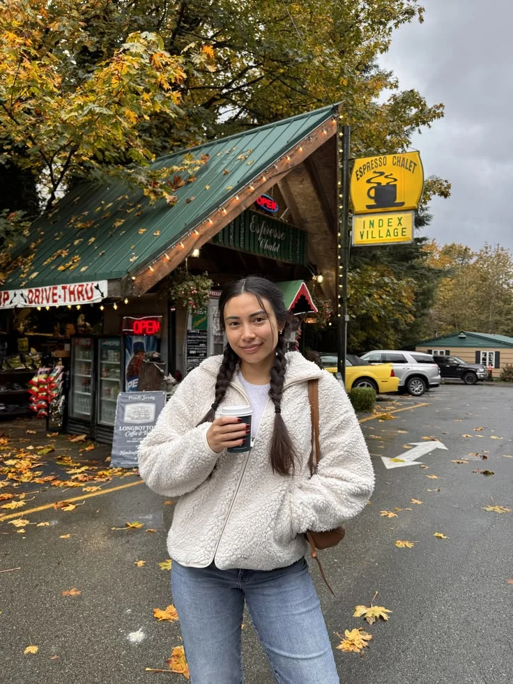 Arabella holding a coffee outside a roadside espresso chalet in fall