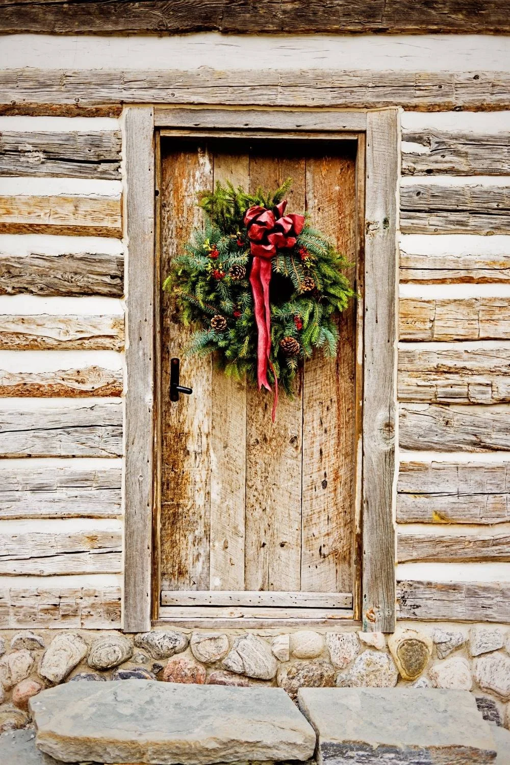 A log cabin door with a Christmas wreath