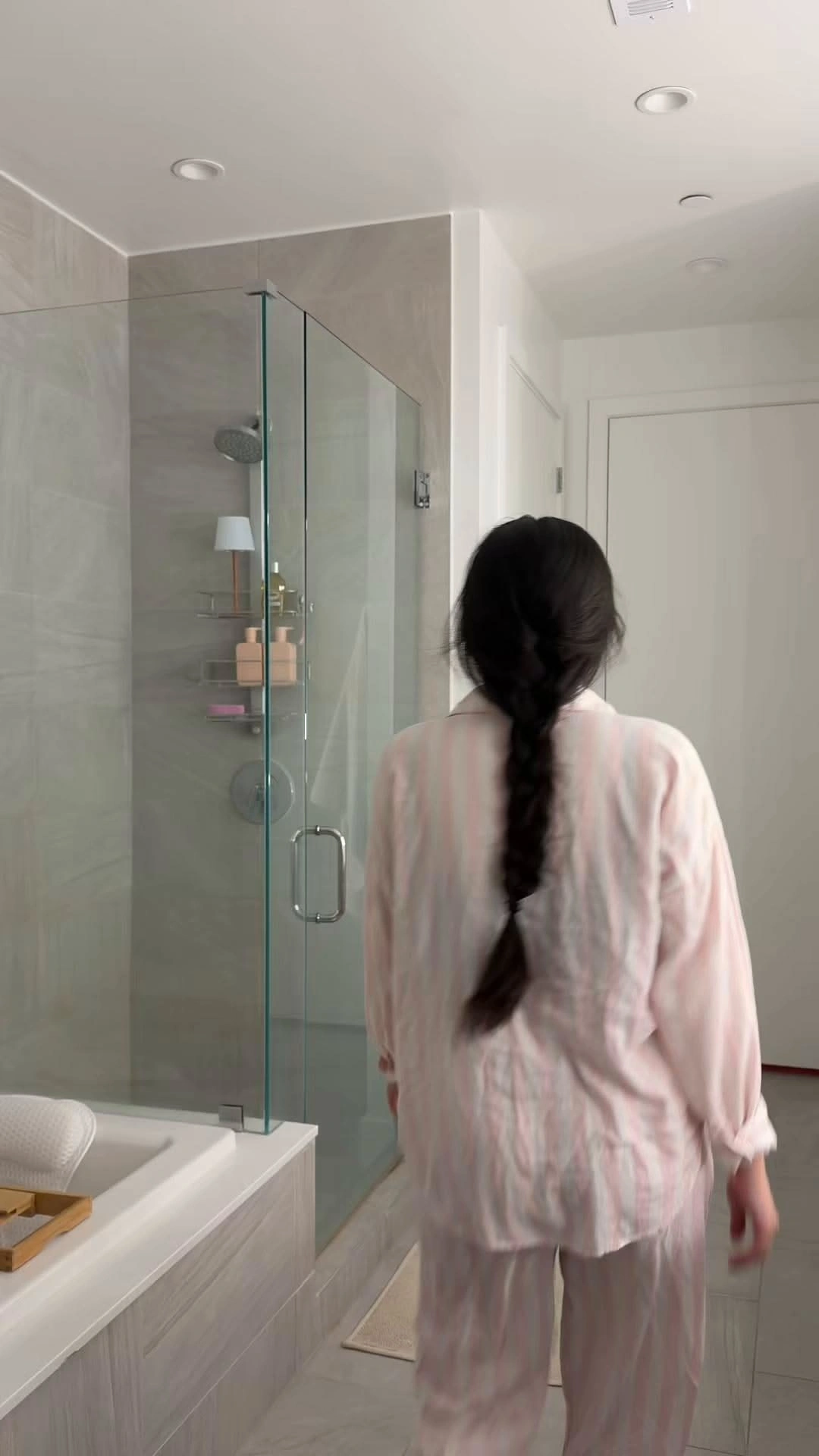Arabella in striped pajamas walking into a bright bathroom