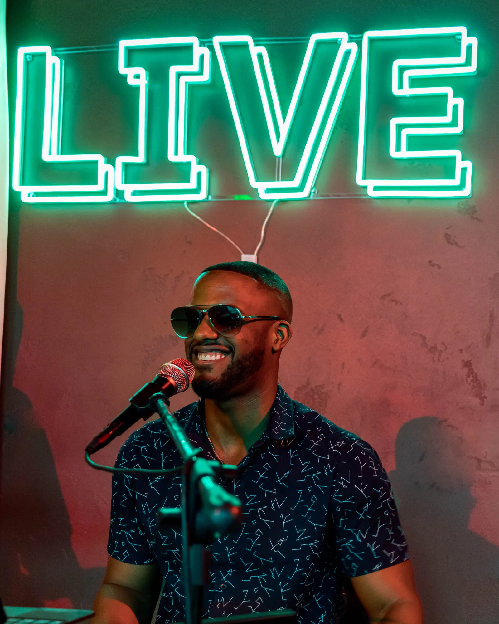 Chops singing under a green LIVE neon sign