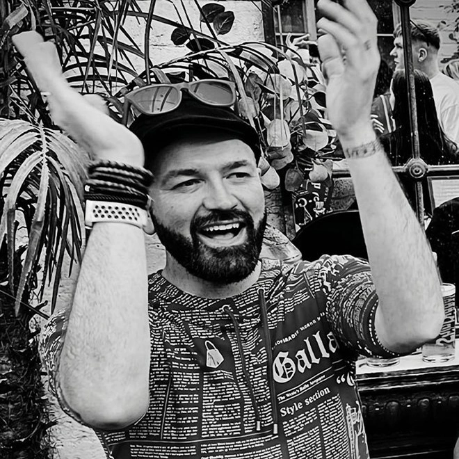 A smiling man in a cap with both hands raised at Wallop
