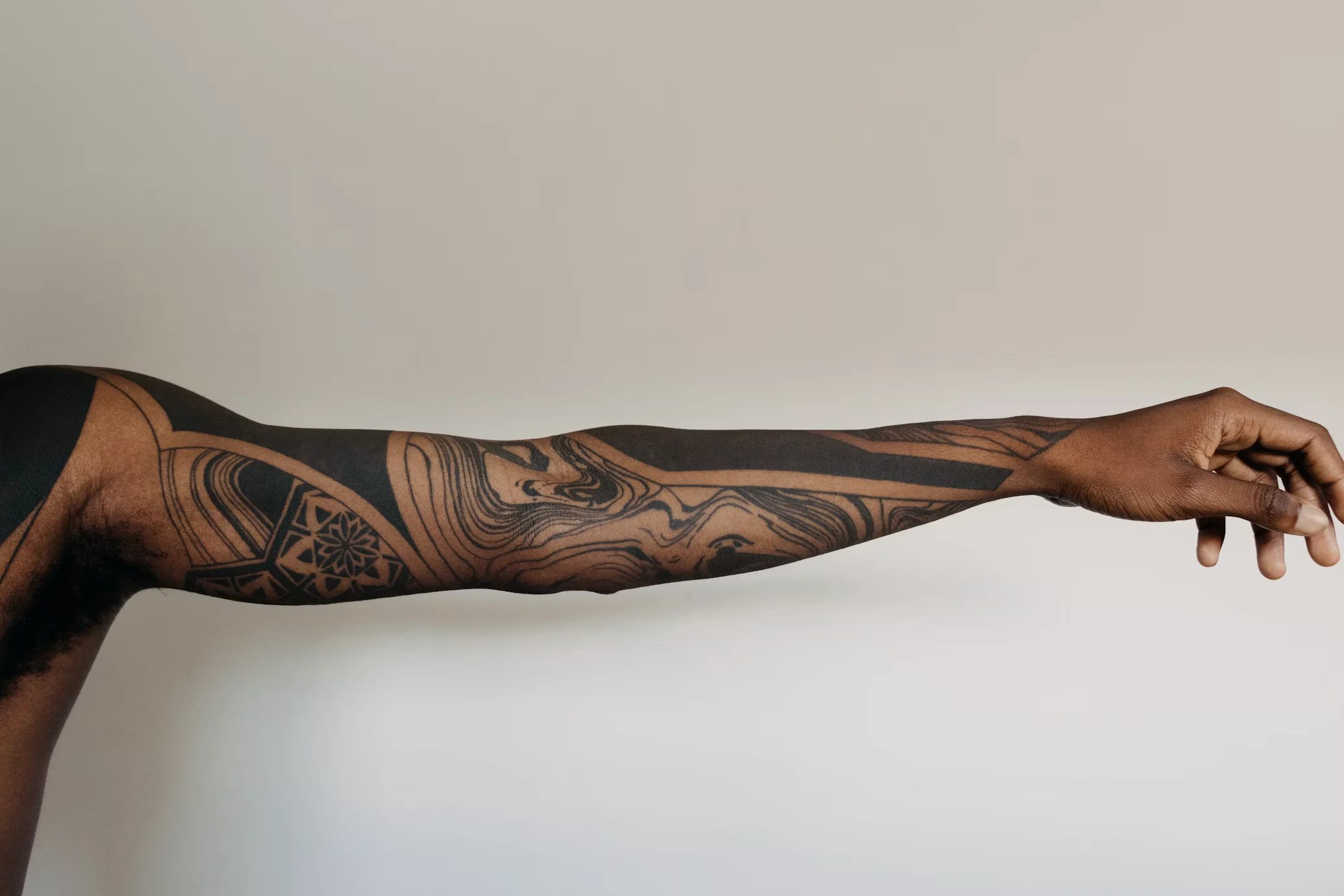 Abstract blackwork tattoo wrapping around a forearm