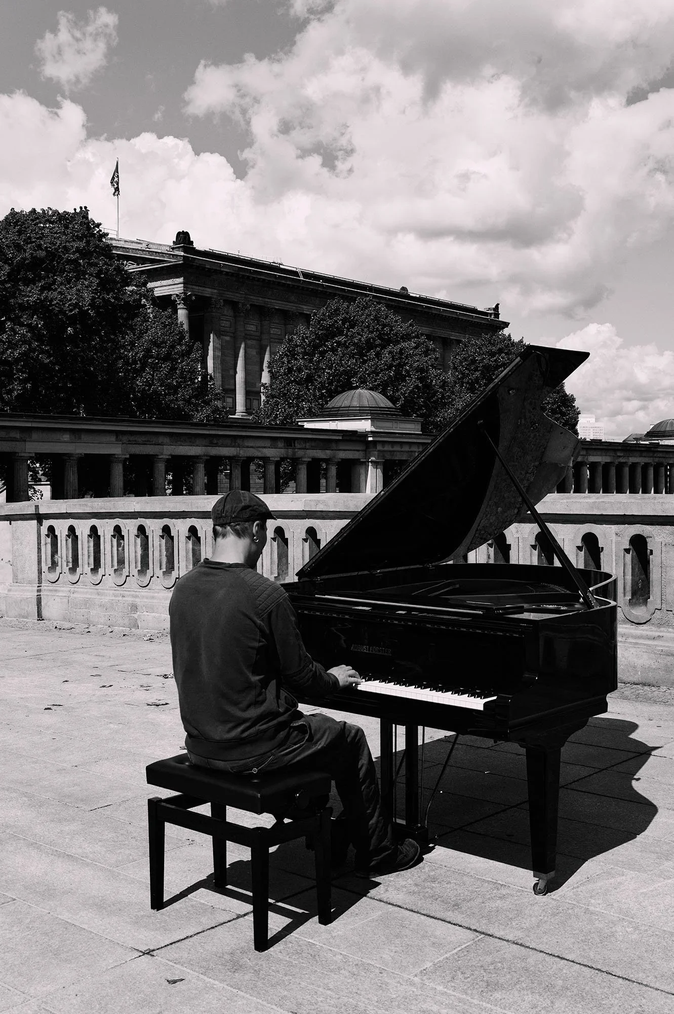 Un uomo suona un pianoforte a coda all’aperto davanti a un museo