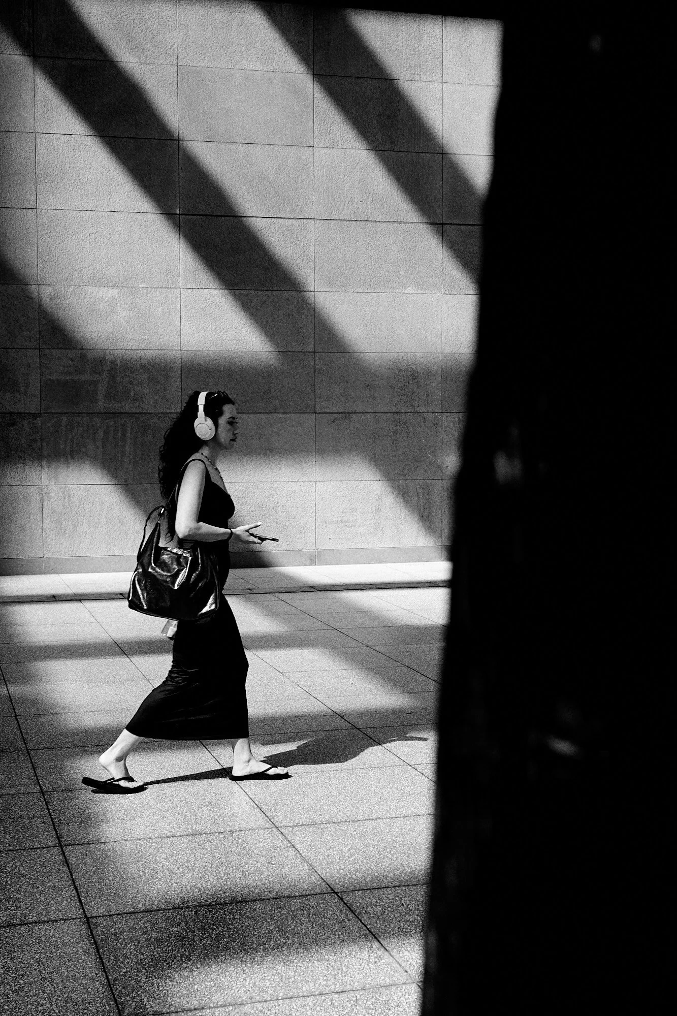 Una donna con le cuffie attraversa strisce di luce e ombra