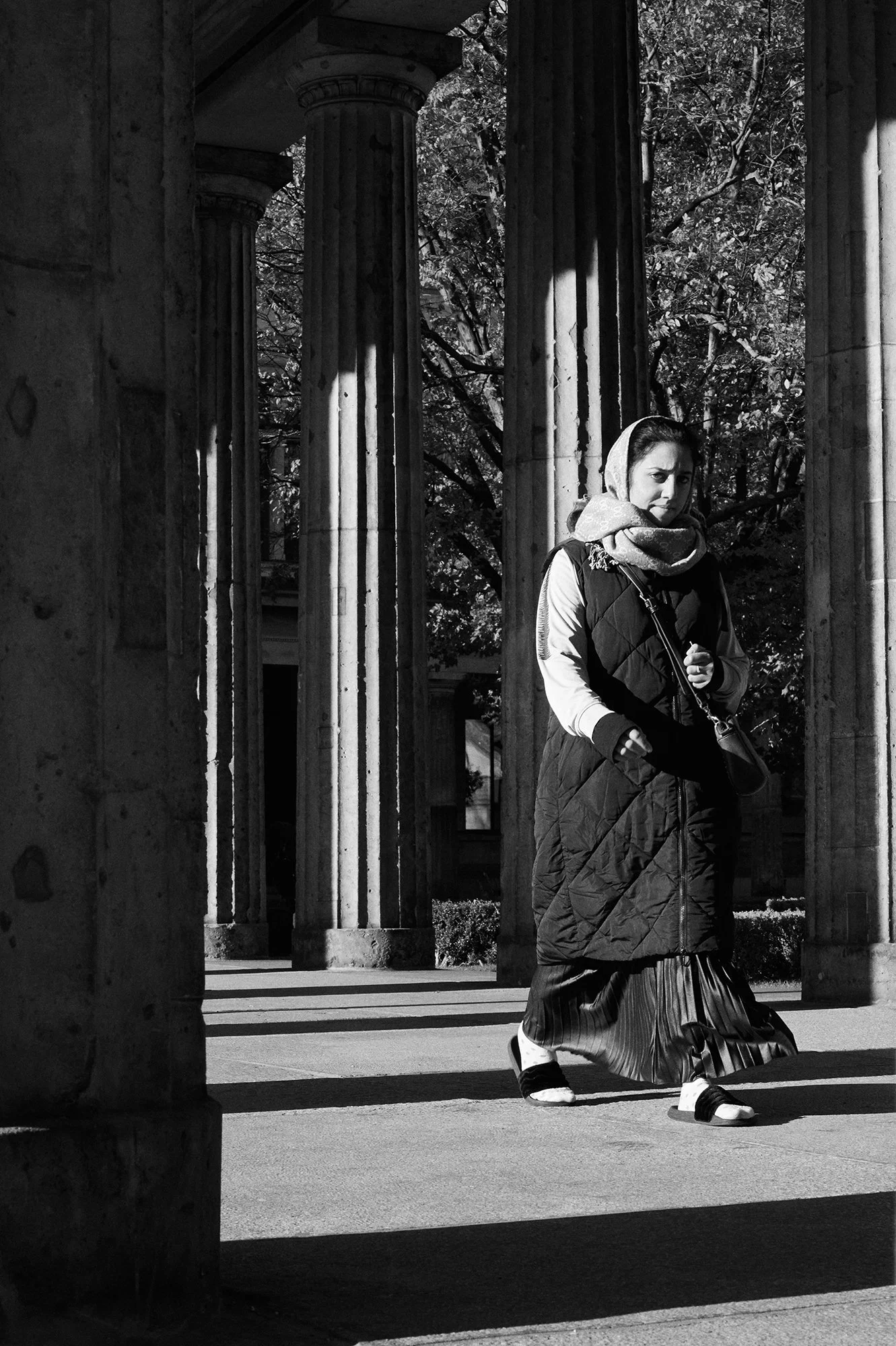 Una donna con il velo cammina tra le colonne nella luce radente