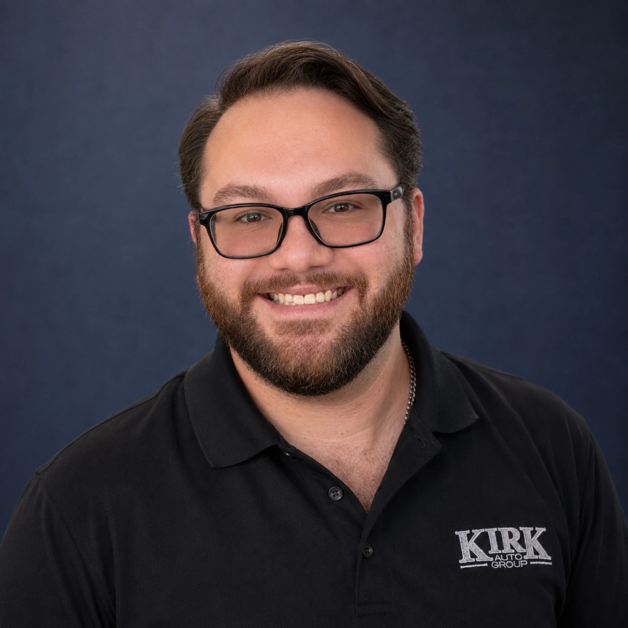 Colt Tabor smiling in glasses and a black Kirk Auto Group polo