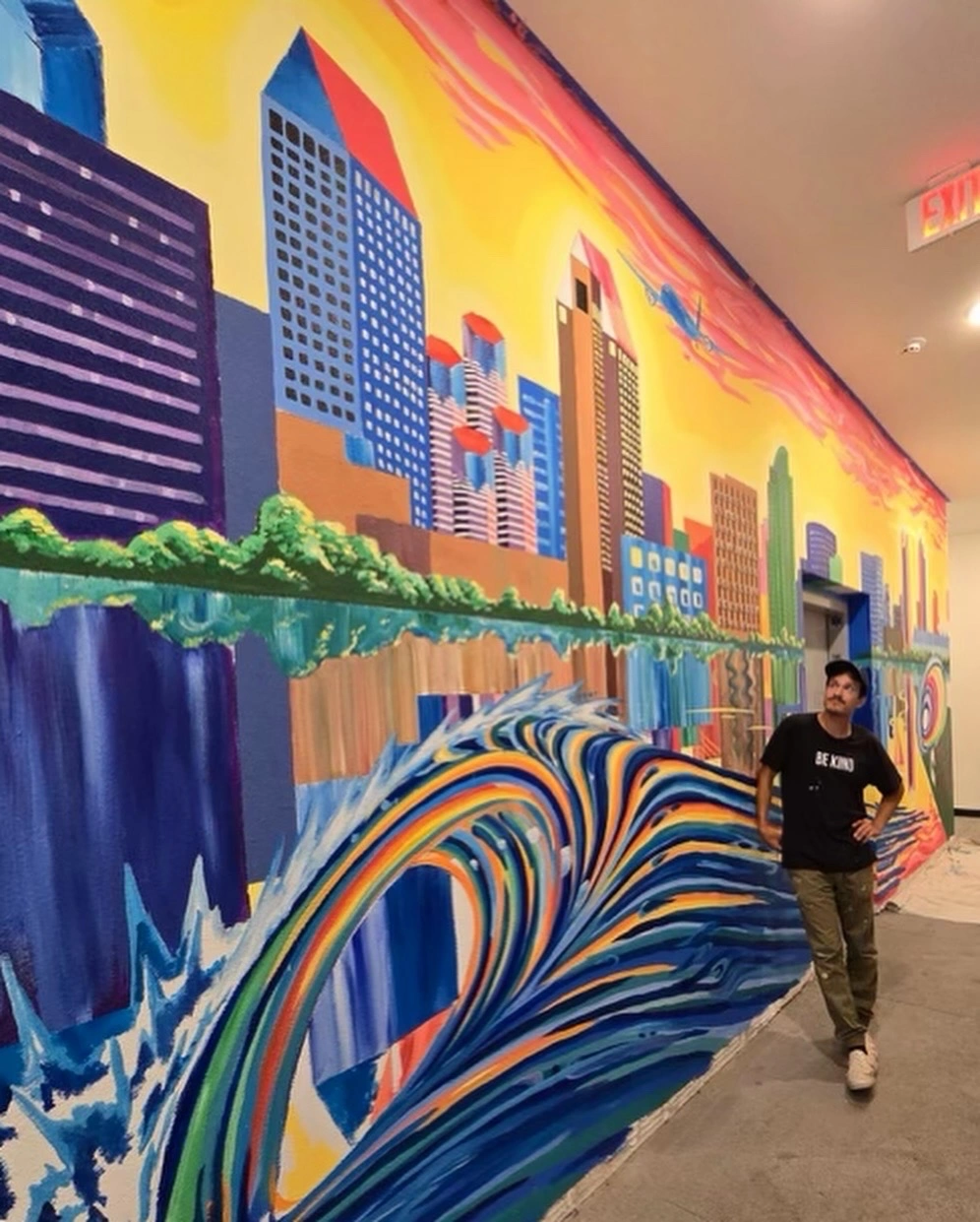 Gonzalo beside his San Diego skyline and wave mural at Stateside Apartments