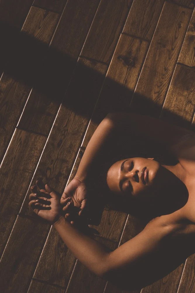 Body-confidence portrait photographed on a warm wooden floor