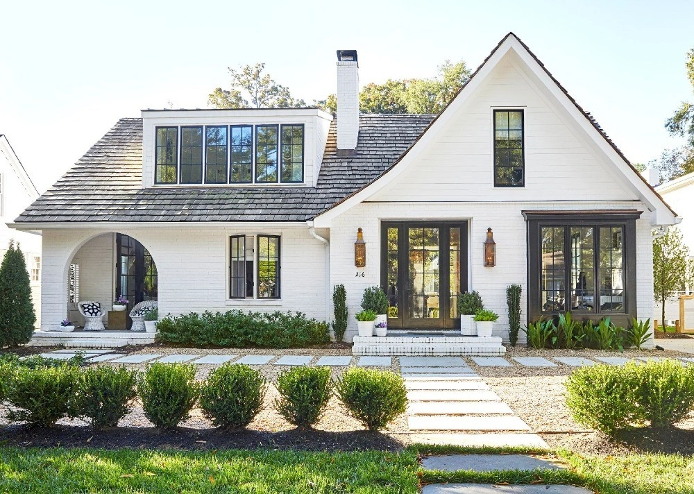 White cottage-style house with black-framed windows and a stone path