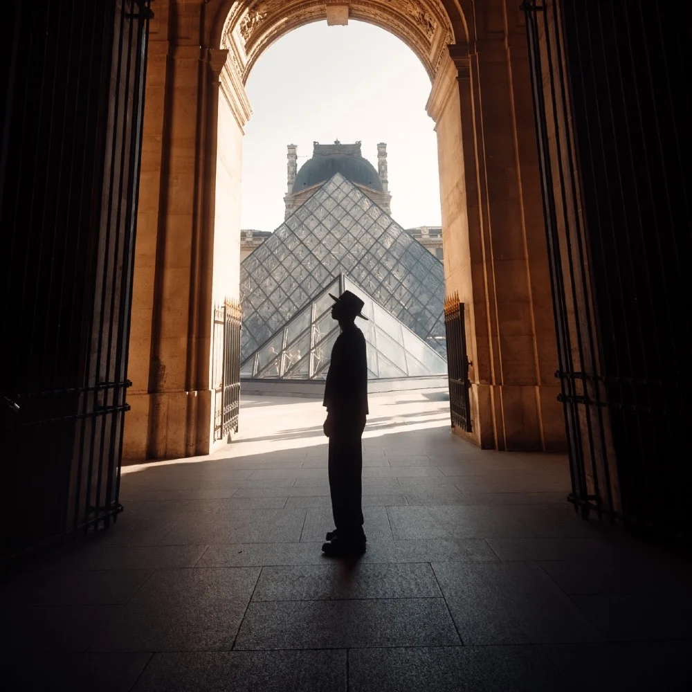 ALZA bajo un arco frente a la pirámide del Louvre