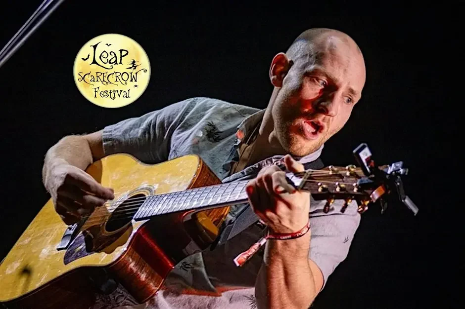 Fin Furey singing energetically while playing acoustic guitar