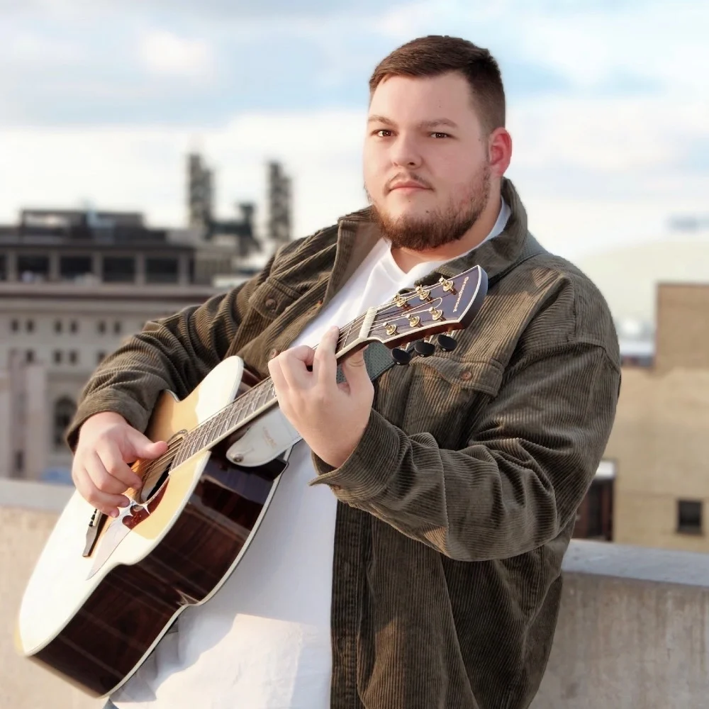 Connor Roy holding an acoustic guitar