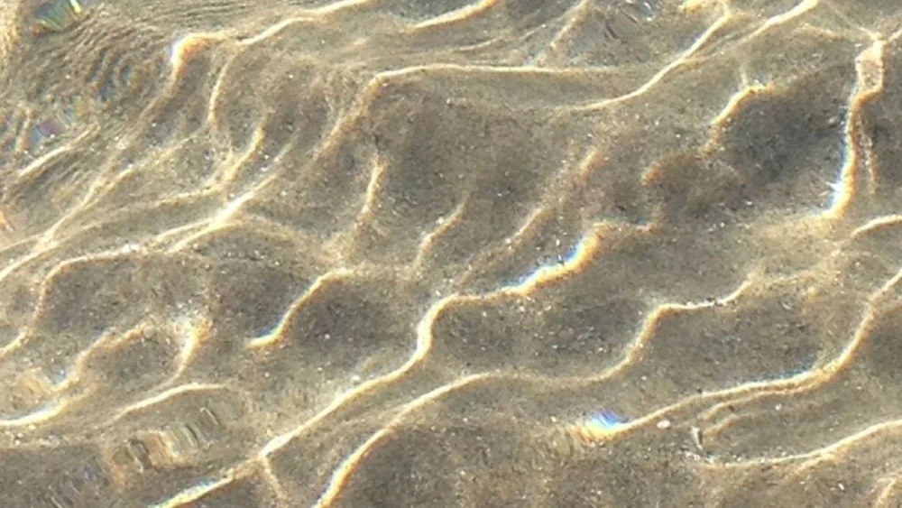 Sunlight moving across shallow sand