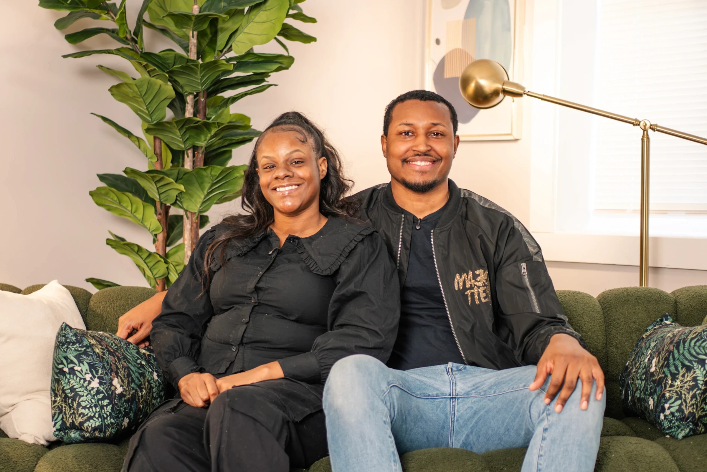 A smiling couple sitting together on a green couch