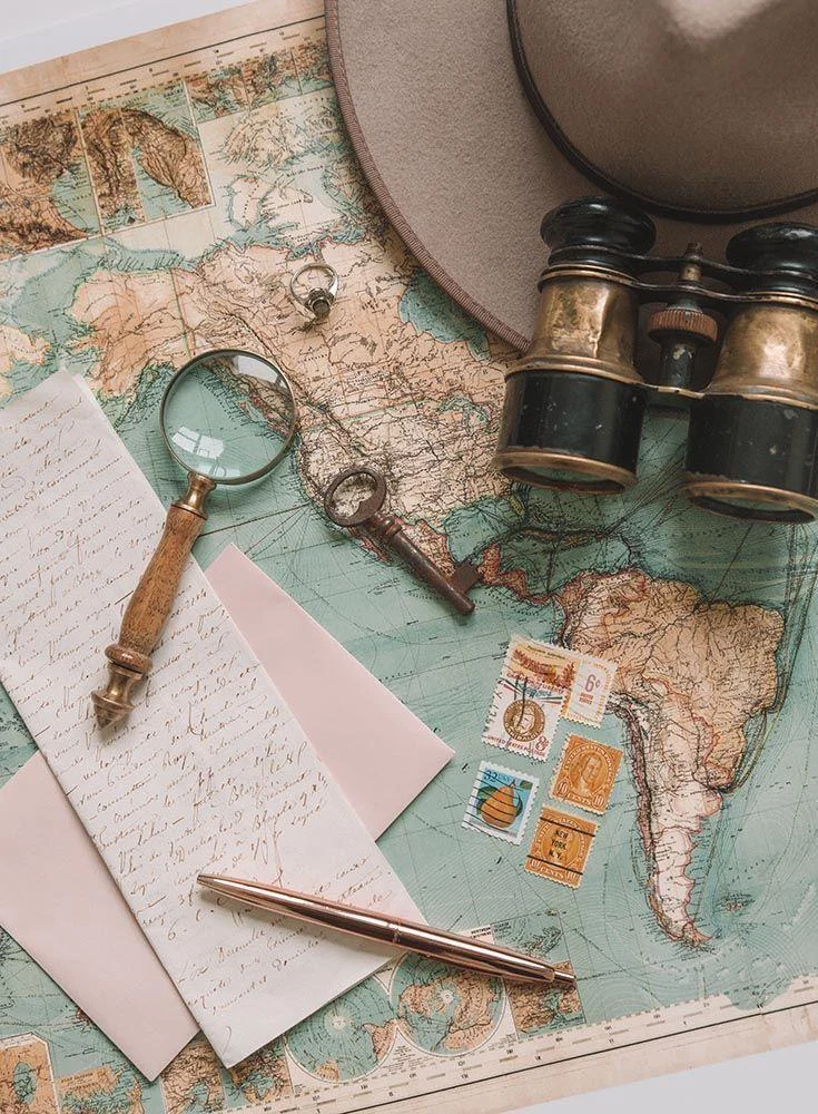 Travel map with binoculars, postcards and a magnifying glass