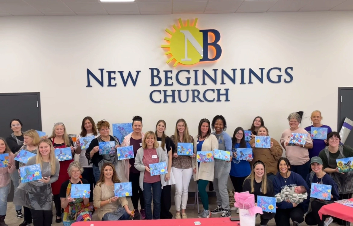 Congregation gathered in front of the New Beginnings logo wall