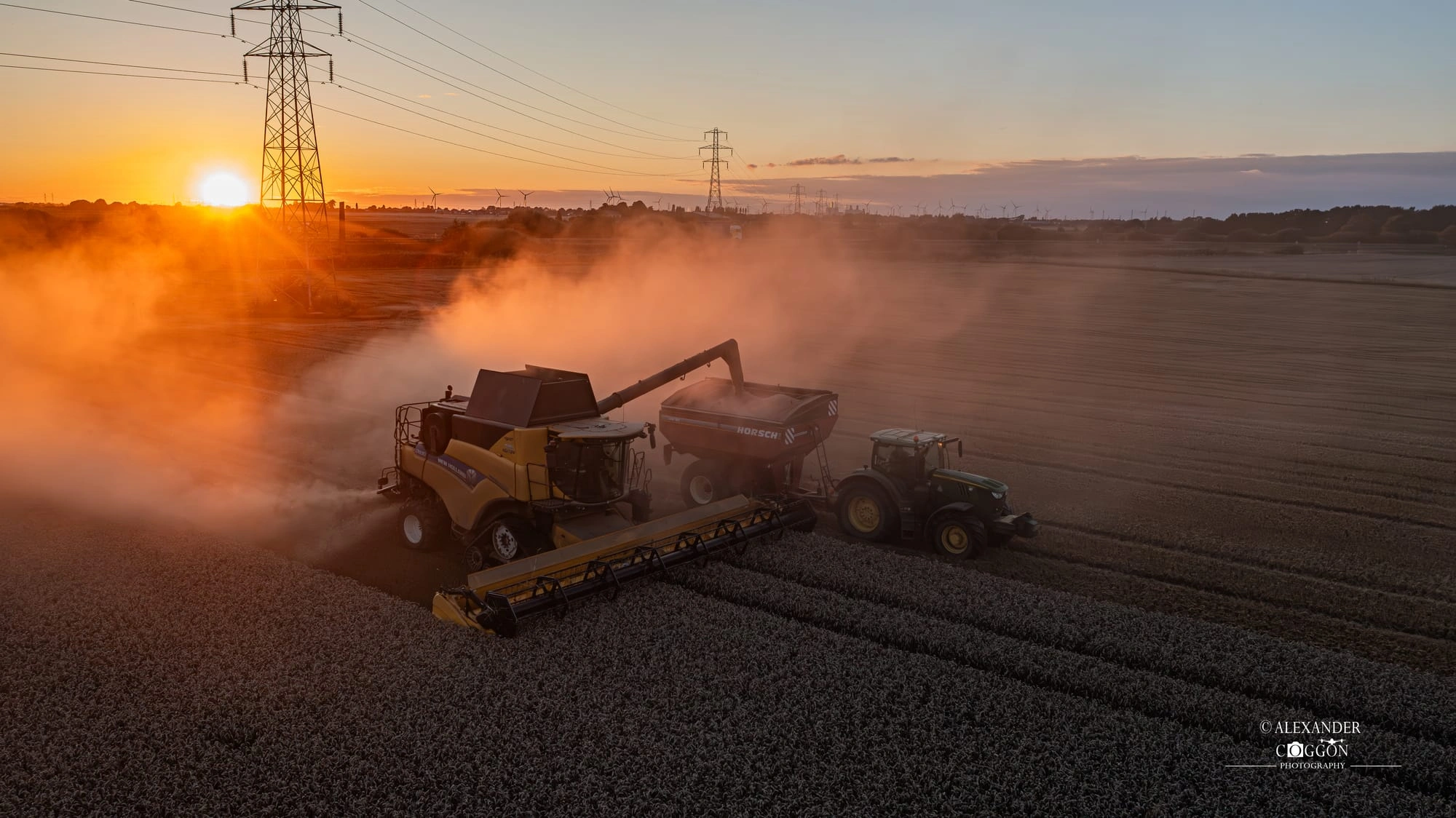 Combine harvesting at sunset beside a pylon