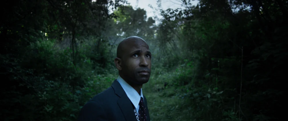 Man in a suit standing on a wooded path in Samuel Laubscher's cinematography reel