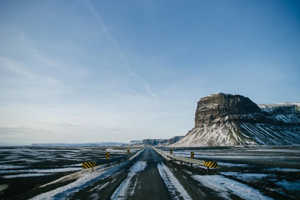 Snow-covered road leading toward a mountain