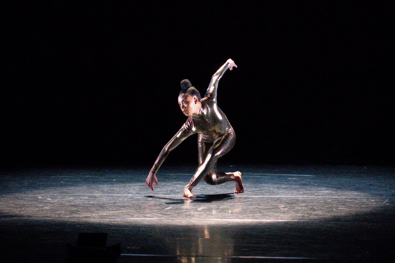 Marcella Lewis crouching low in a pool of light during the solo Show Pony