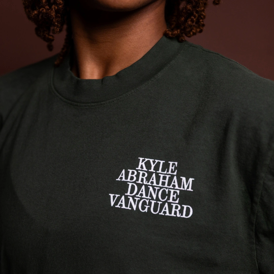 A dark green long sleeve with the stacked Kyle Abraham Dance Vanguard wordmark