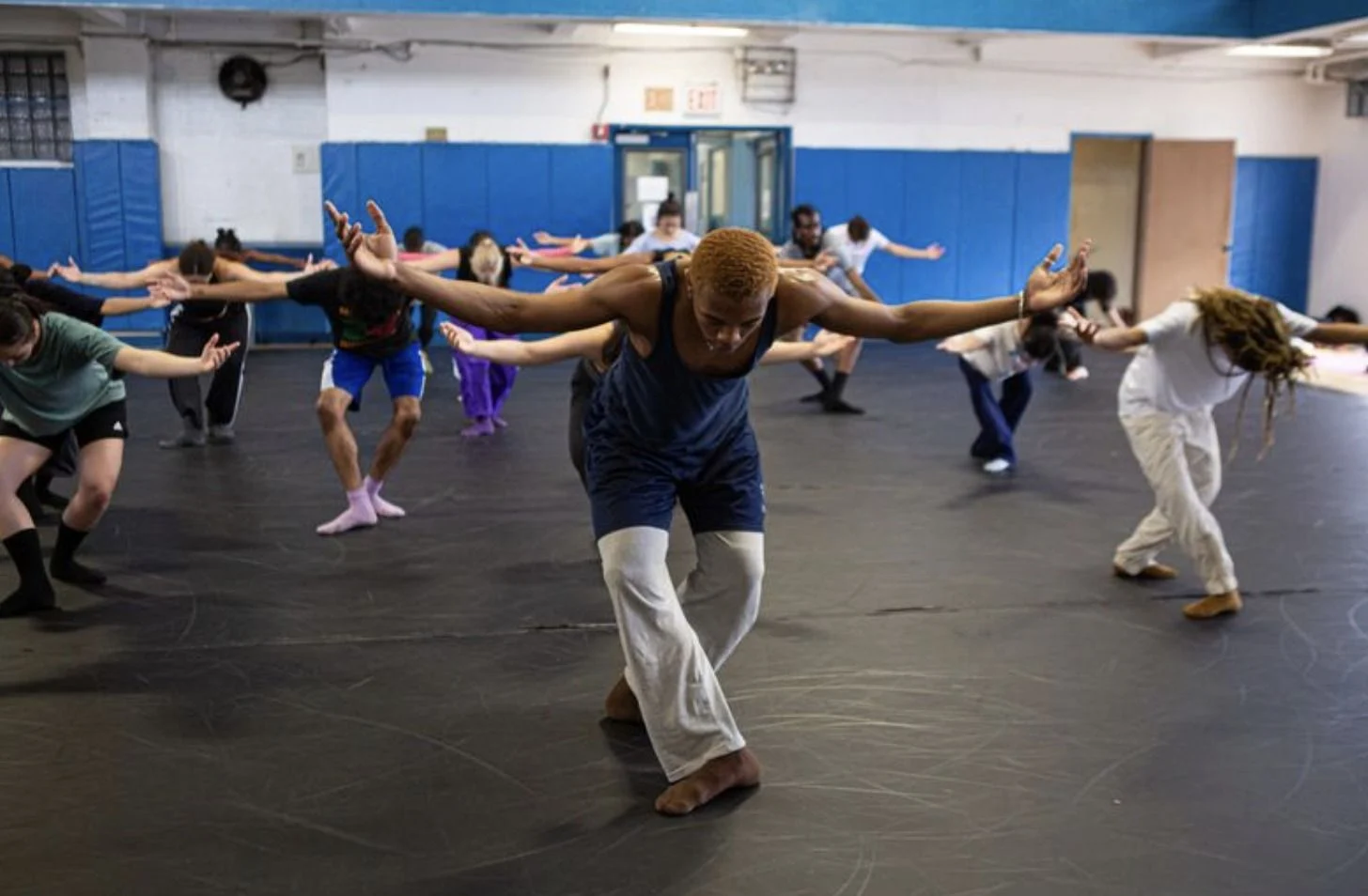 A dance class reaching their arms out in unison