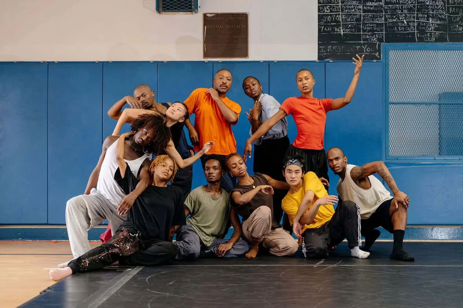 Dancers posed together on a studio floor with blue padded walls