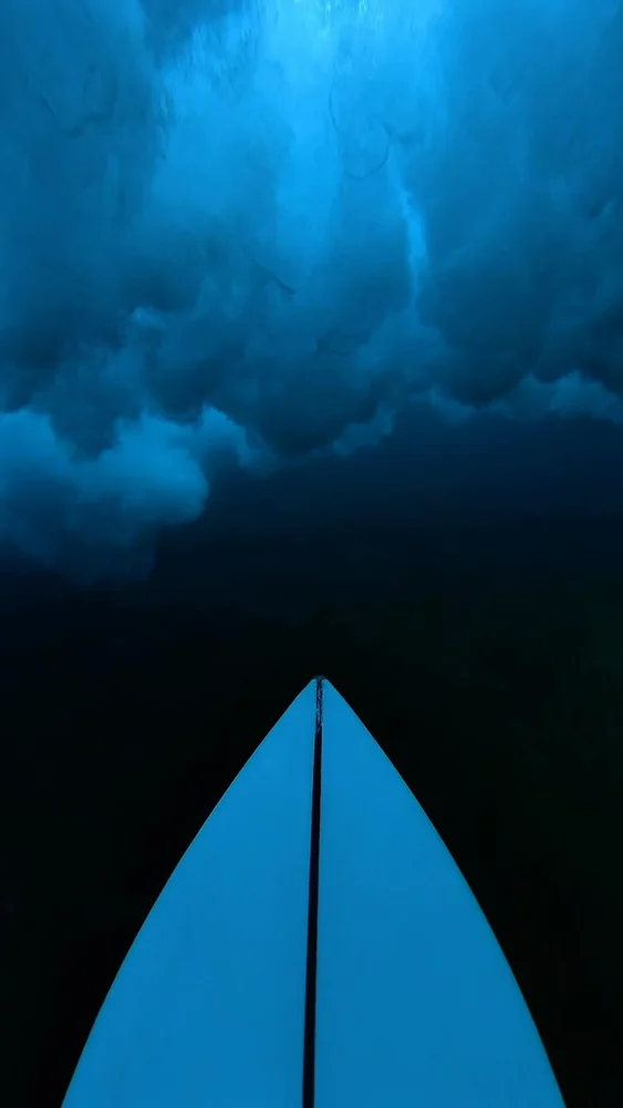 Point-of-view surfboard beneath a breaking wave