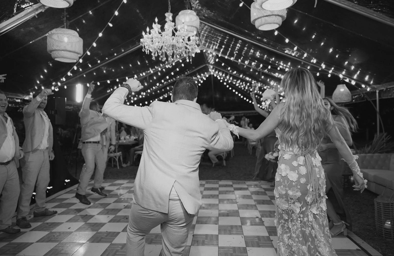 Black-and-white celebration scene with a couple dancing under lights