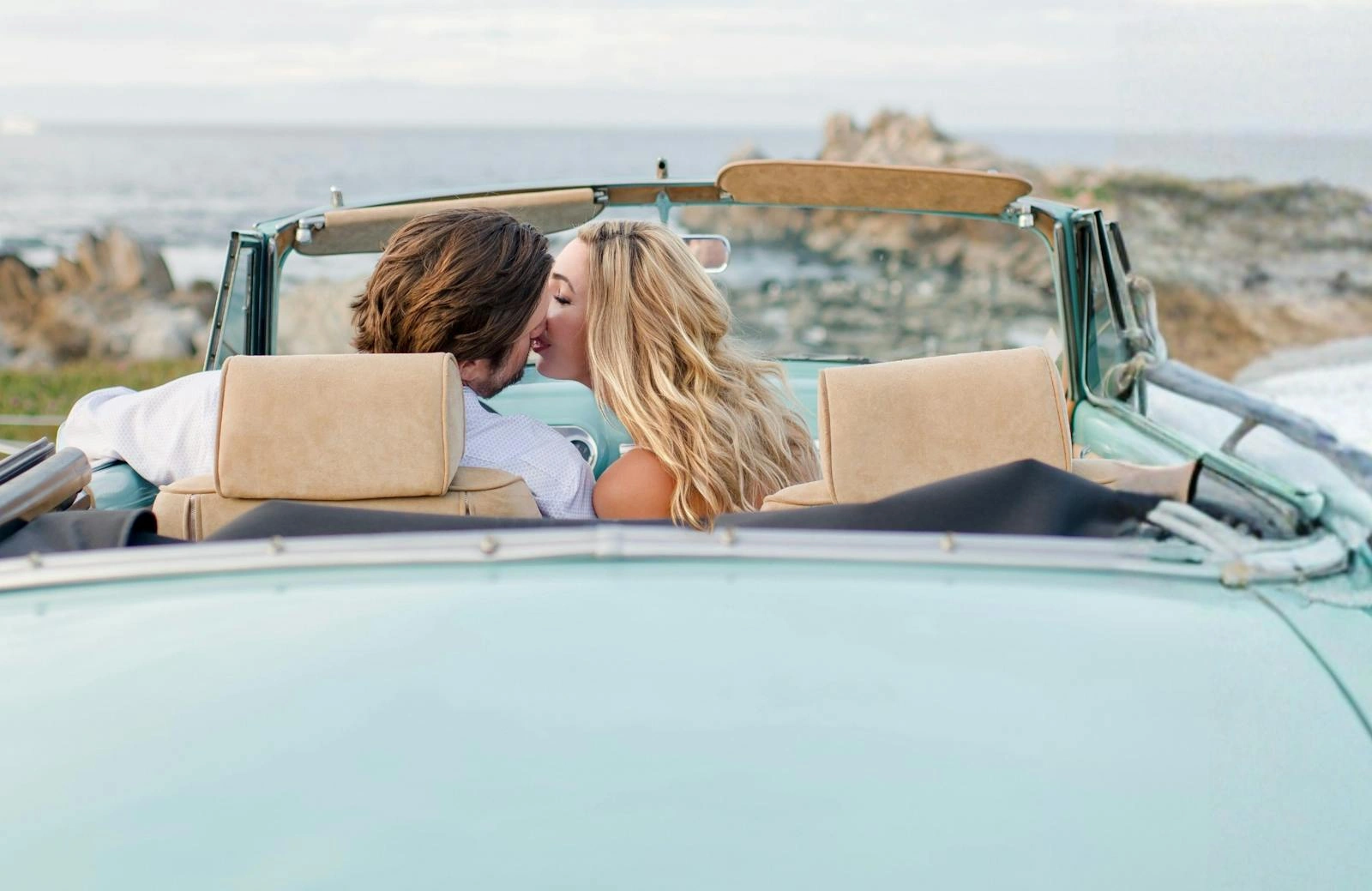 Couple in a vintage convertible beside the coast