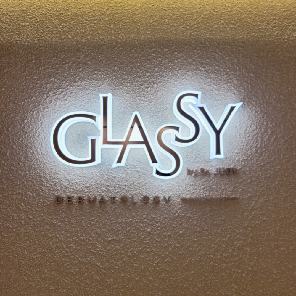 Illuminated GLASSY Dermatology sign on a textured beige wall