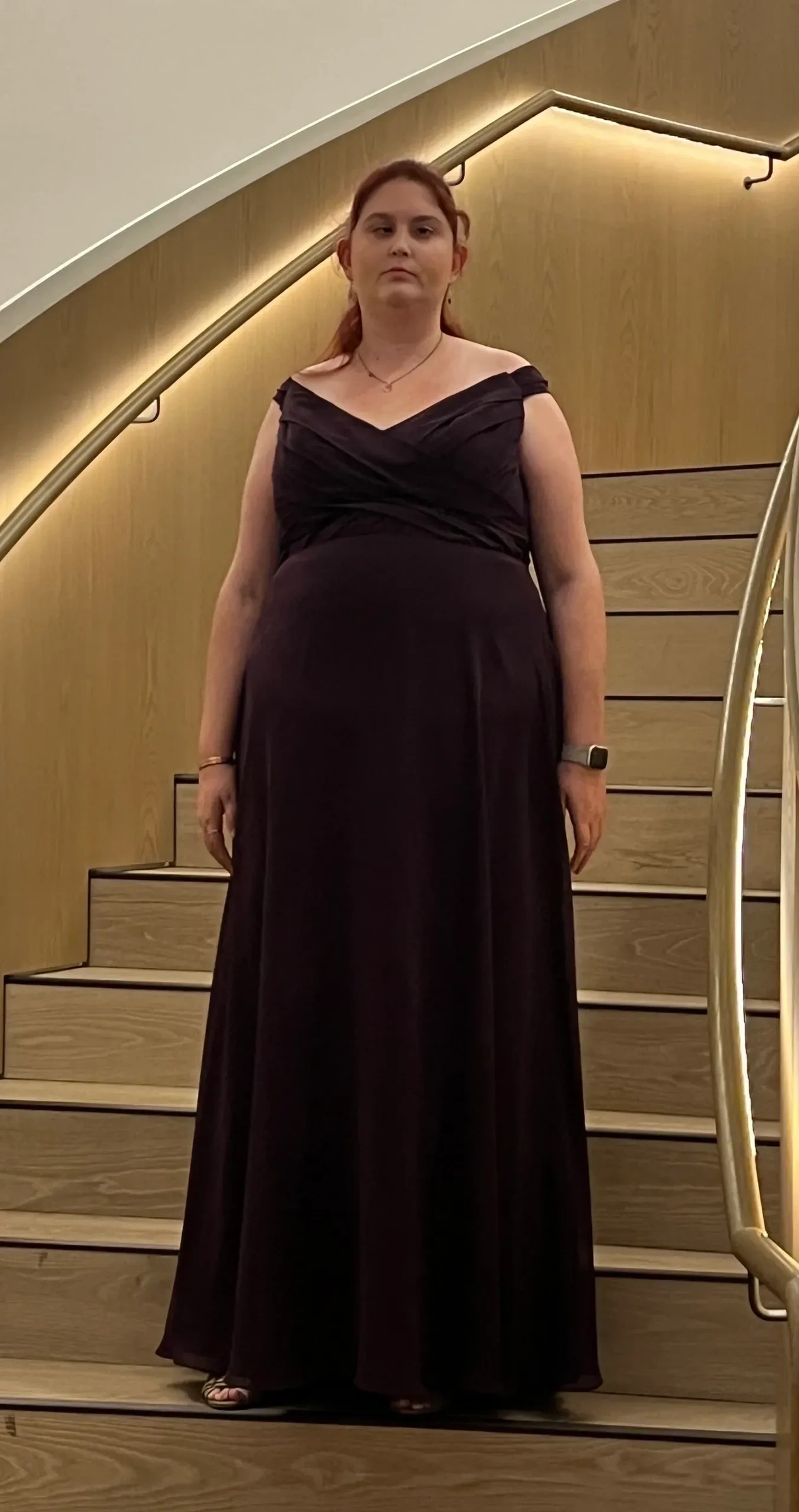 Kirsten Busby in an evening gown on a staircase